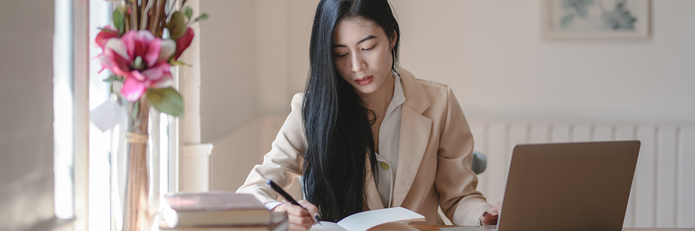A person writing and typing on a computer.