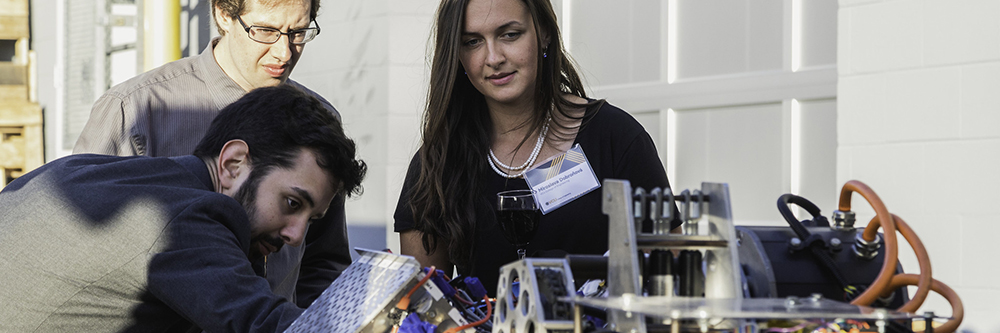 Students and trainer stand over equipment at the VCU Maker Garage