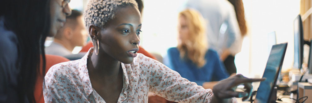 Woman shows another woman information on a computer